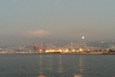 Large orange tinted Harvest Moon appearing over Beirut at sunset time